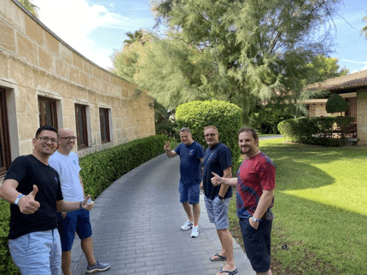 Fünf Kollegen von SimplyTest stehen beim Jahresworkshop auf Mallorca vor einem Natursteinhaus