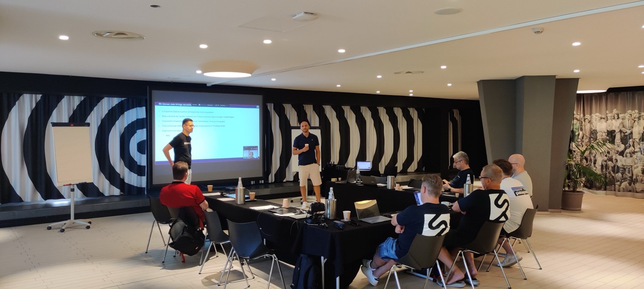 Workshop im Tagungsraum mit Präsentation und Teilnehmern an Tischreihen