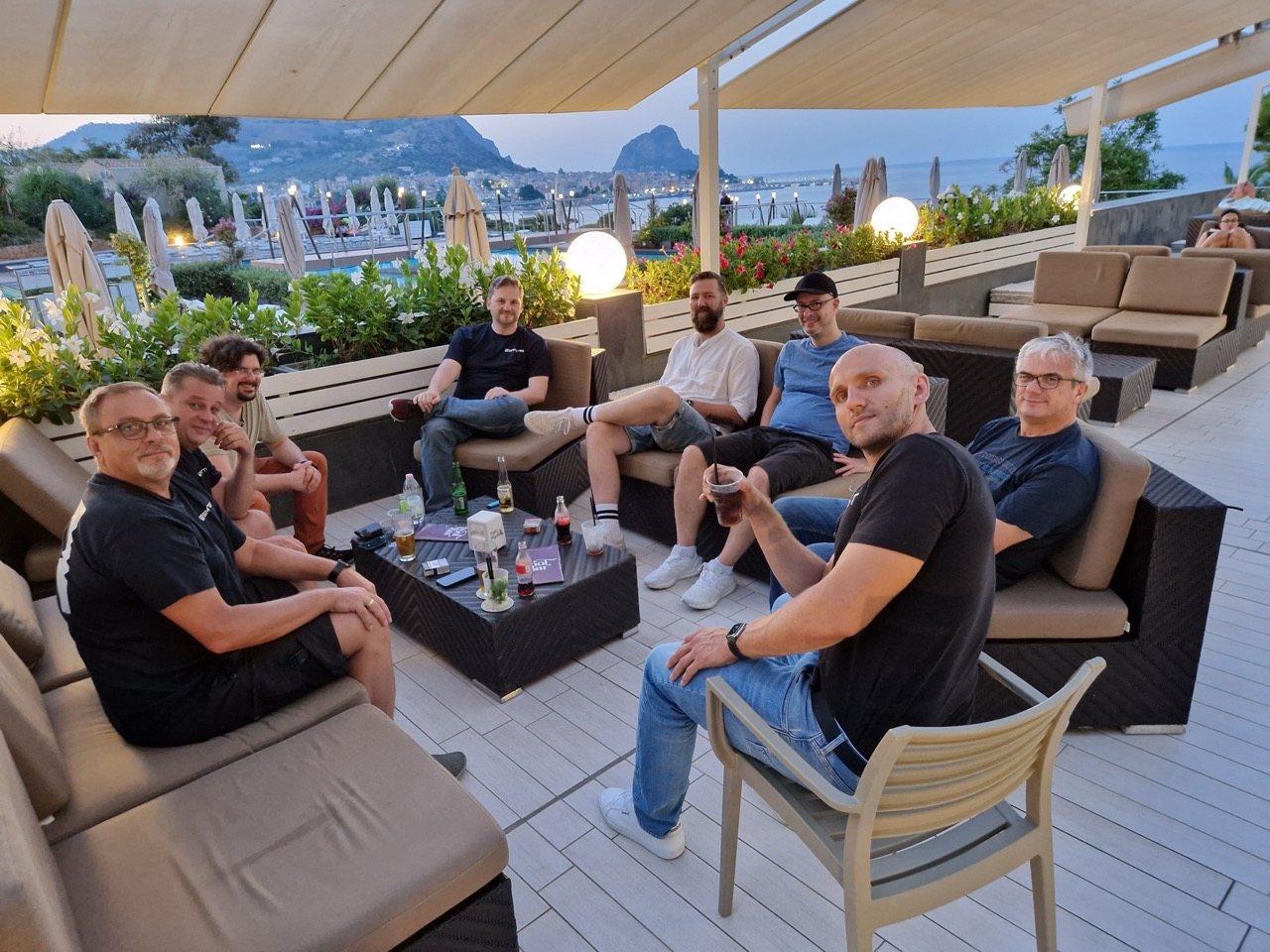 Das Team sitzt am Abend auf einer Dachterrasse mit Blick aufs Meer