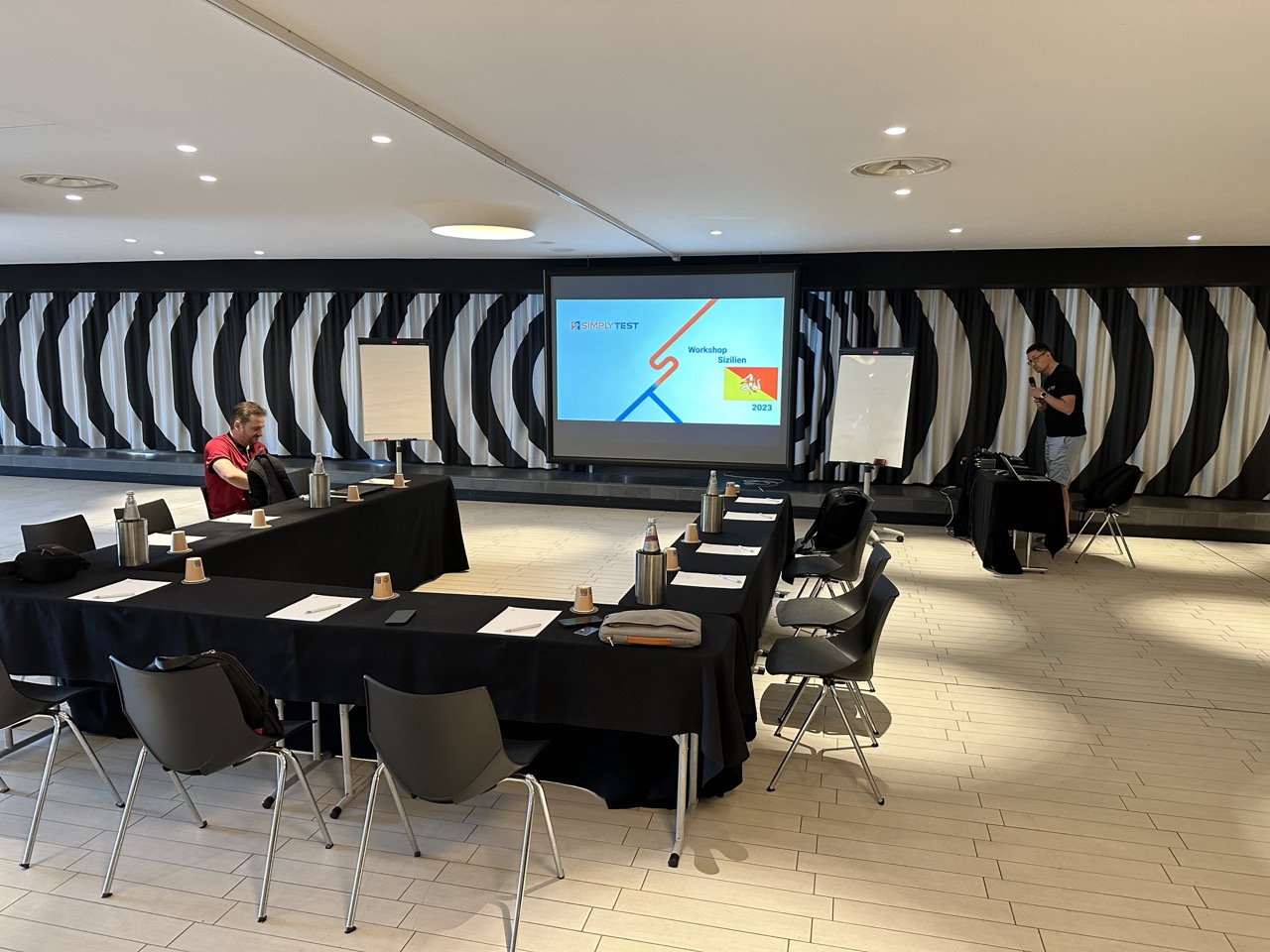 Tagungsraum mit Tischen in U-Form, Leinwand und Flipcharts